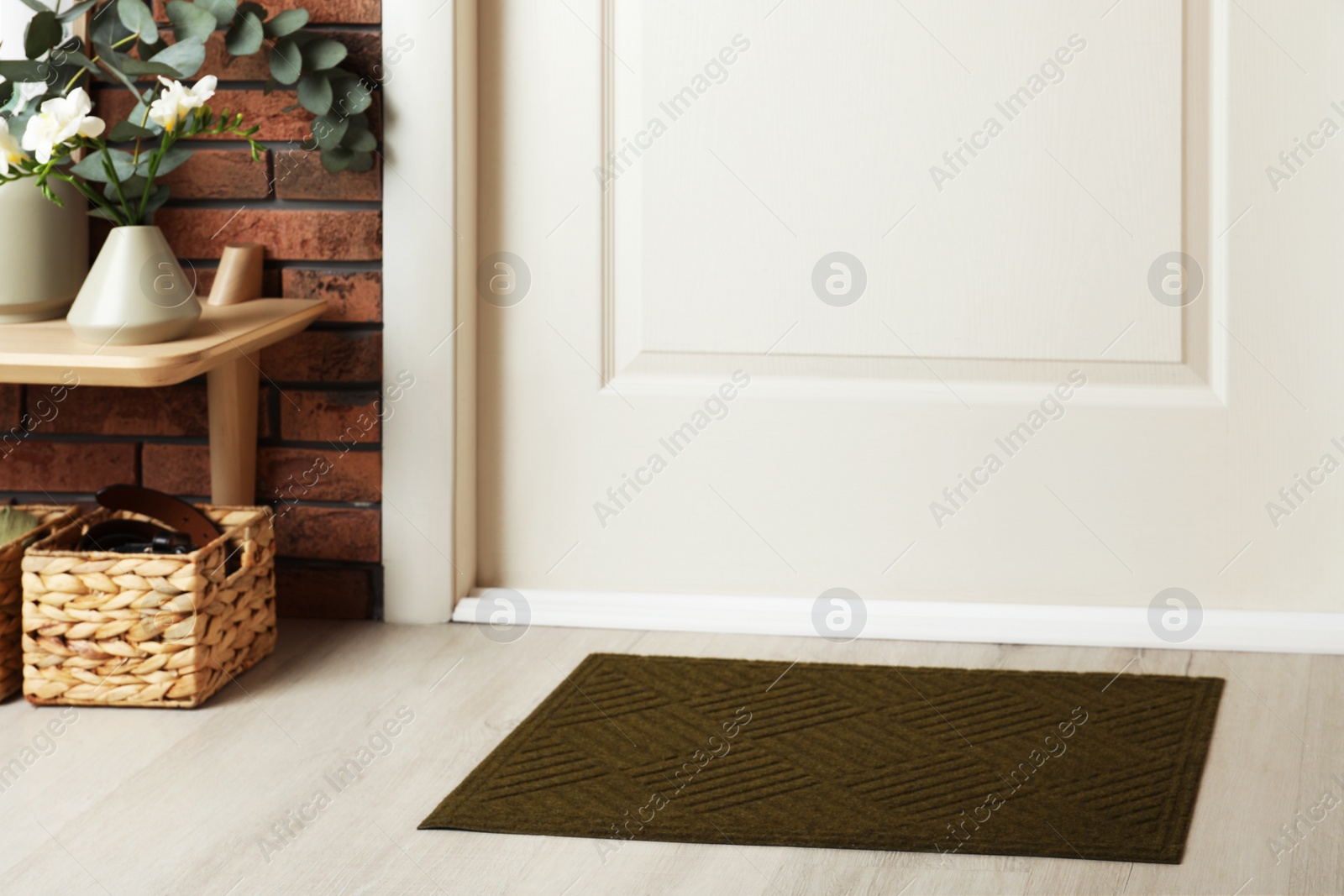 Photo of Dark olive door mat on wooden floor in hall