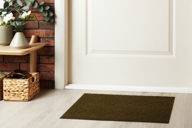 Dark olive door mat on wooden floor in hall