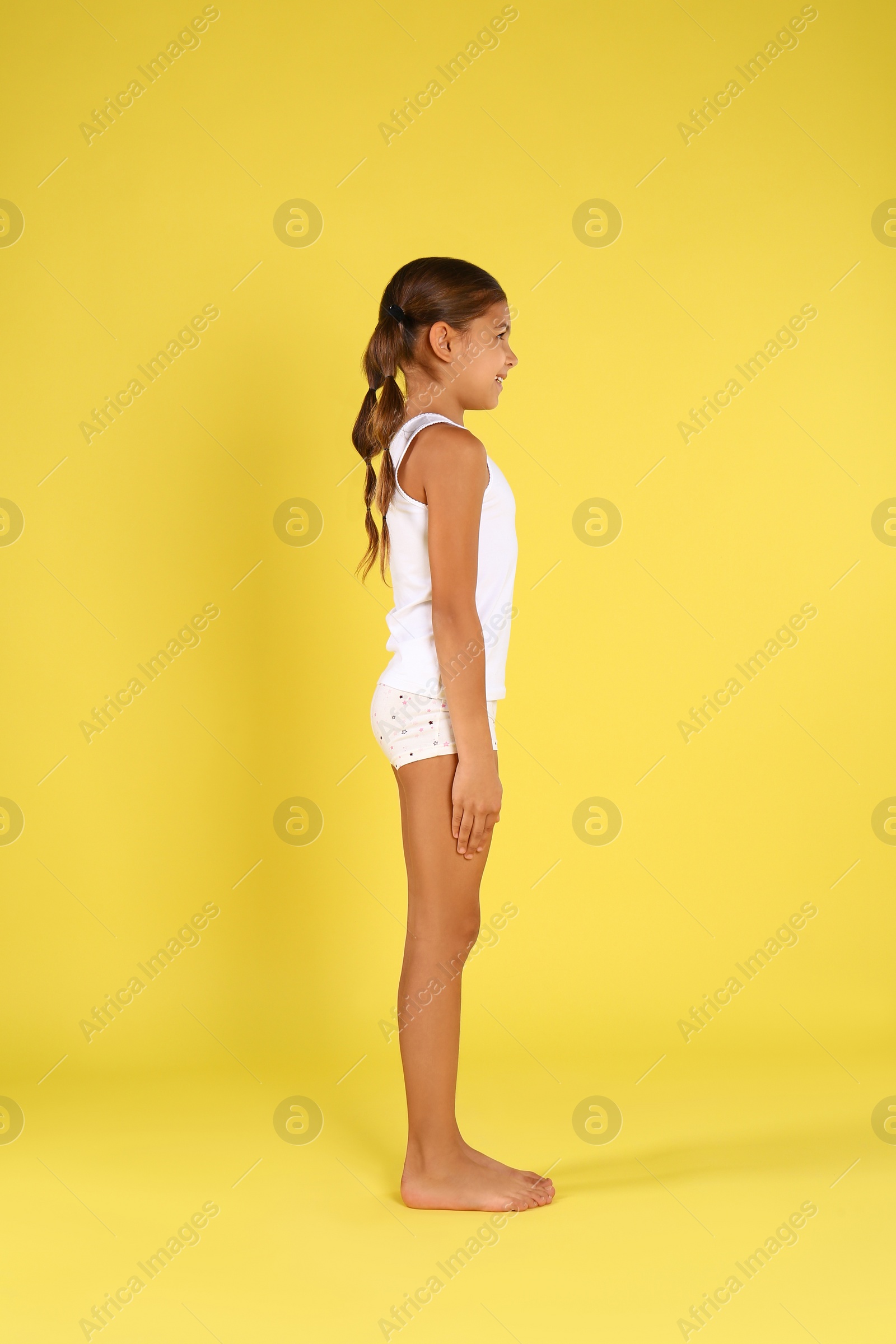 Photo of Cute little girl in underwear on yellow background