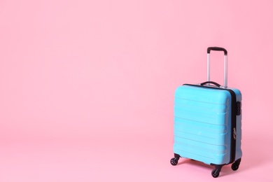 Photo of Modern blue suitcase on light pink background. Space for text