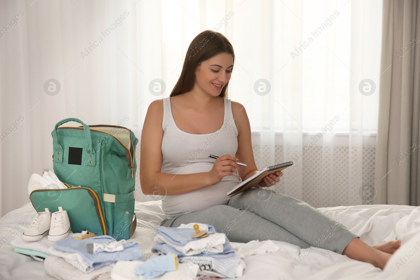 Photo of Pregnant woman packing bag for maternity hospital at home