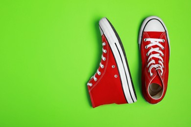 Photo of Pair of new stylish red sneakers on light green background, flat lay. Space for text