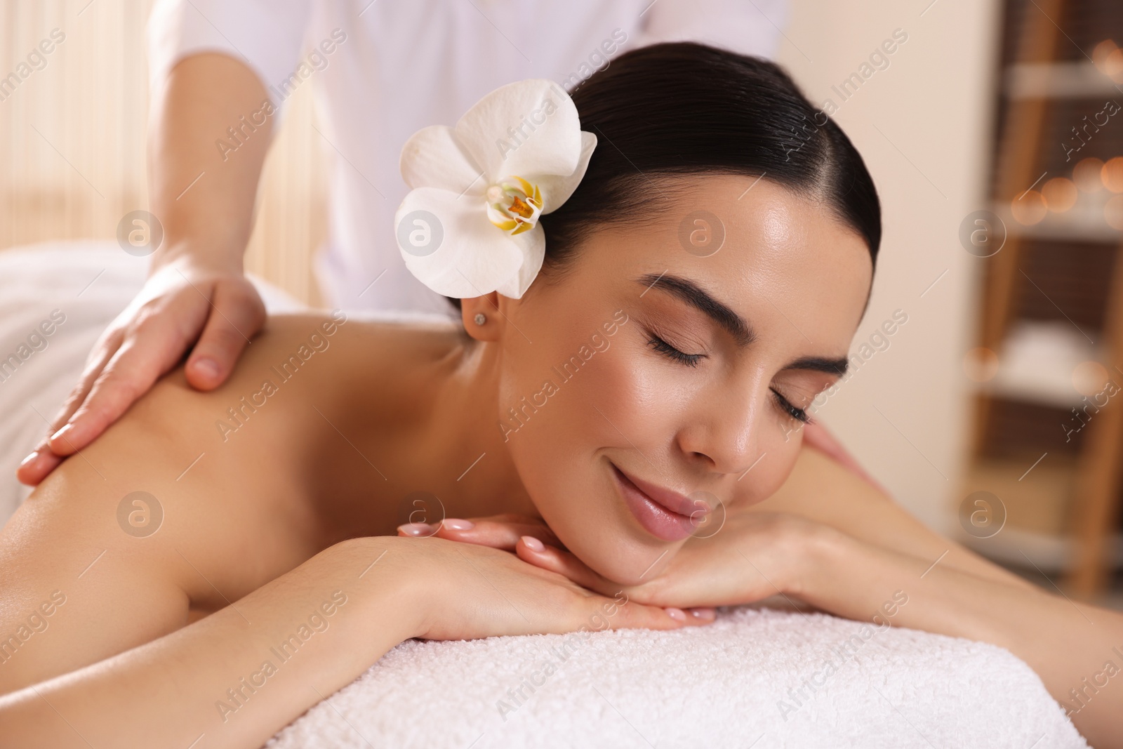 Photo of Young woman enjoying professional massage in spa salon