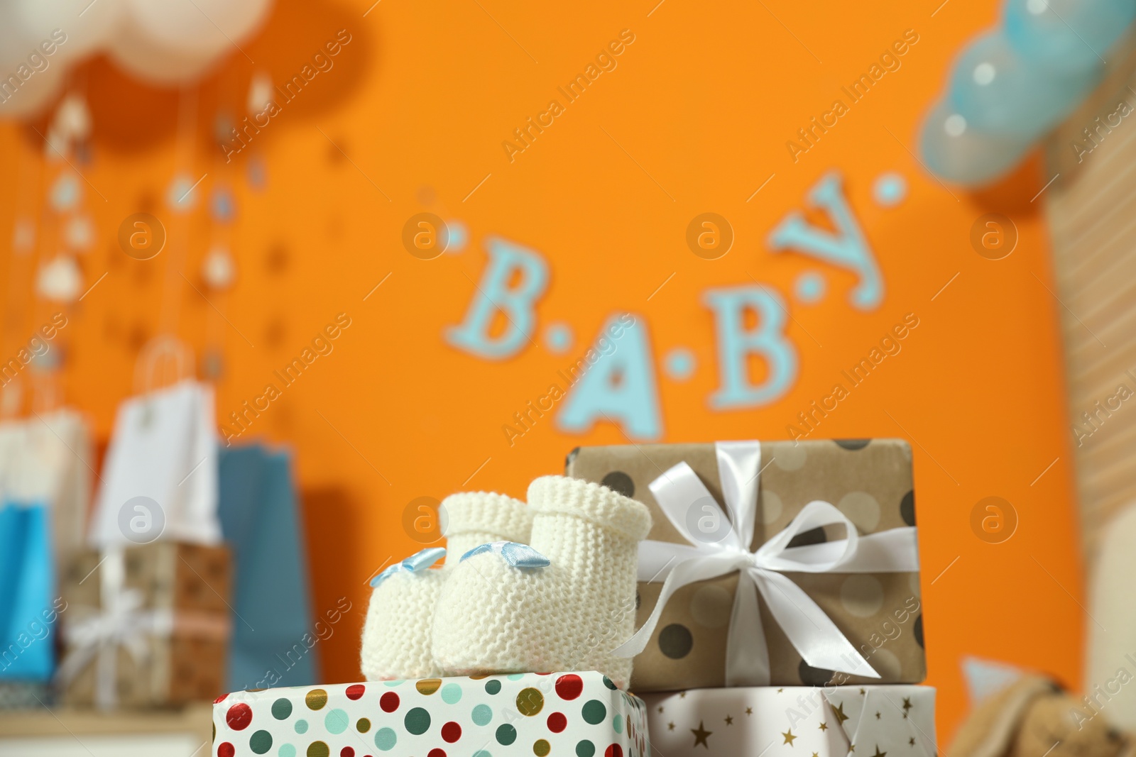 Photo of Baby shower party. Festive decor, gift boxes and booties in stylish room, space for text