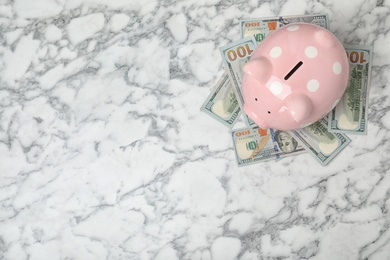 Photo of Piggy bank with money and space for text on table, top view