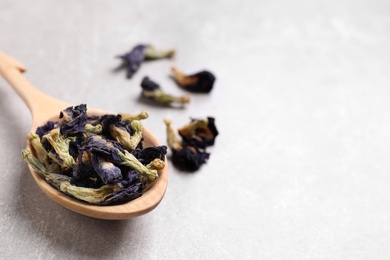 Photo of Spoon and dry organic blue Anchan on light grey table, closeup with space for text. Herbal tea