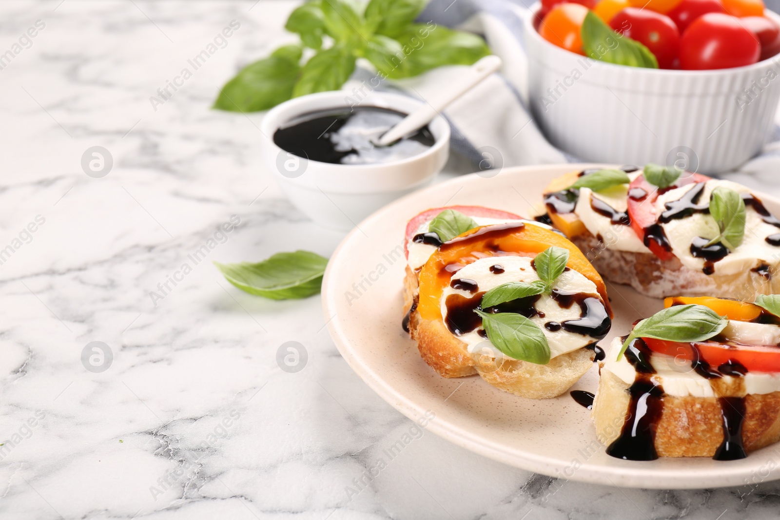 Photo of Delicious bruschettas with mozzarella cheese, tomatoes and balsamic vinegar on white marble table, space for text