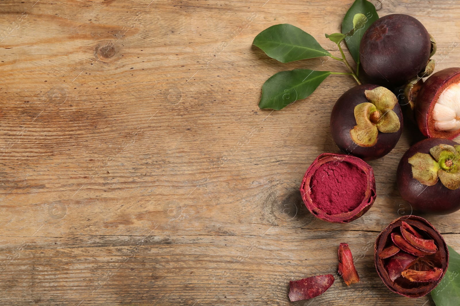 Photo of Purple mangosteen powder and fruits on wooden table, flat lay. Space for text