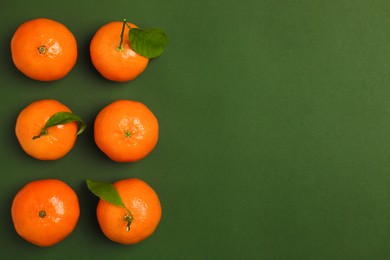 Delicious tangerines and leaves on green background, flat lay. Space for text