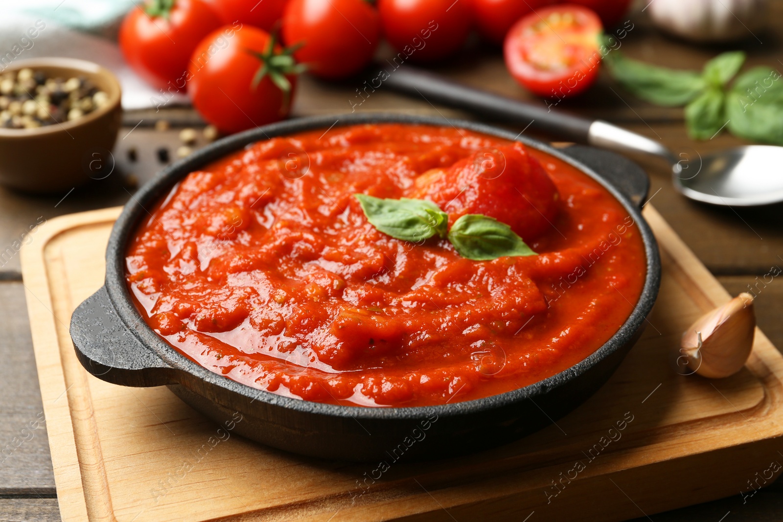 Homemade tomato sauce and basil in bowl on wooden table, closeup Photo of Homemade tomato sauce and basil in bowl on wooden table, closeup