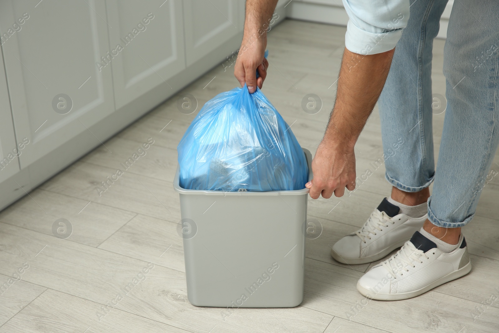 Photo of Man taking garbage bag out of bin at home, closeup