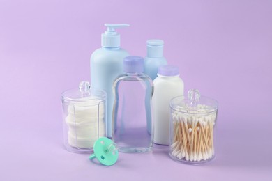 Different skin care products for baby and pacifier on violet background