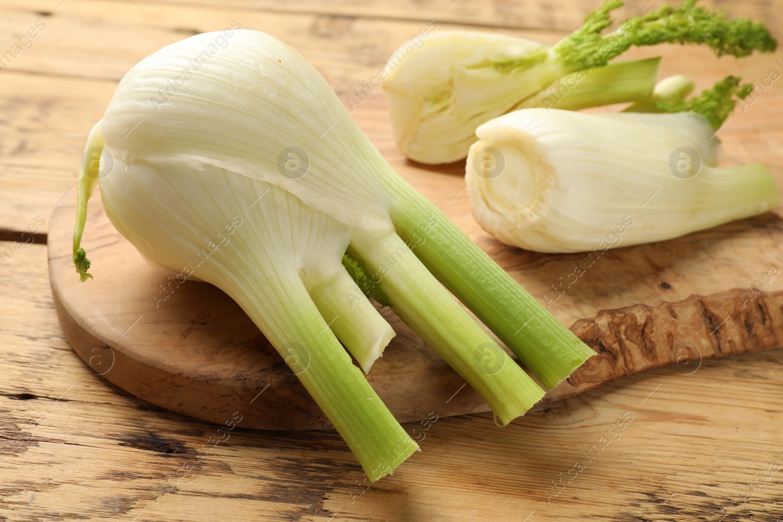 Photo of Fresh raw fennel bulbs on wooden table, closeup