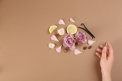 Photo of Woman with perfume. Fragrance composition, flowers and lemon on light brown background,  top view