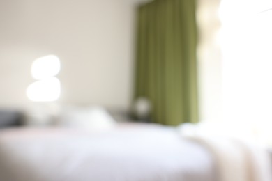 Photo of Blurred view of large bed near window in room