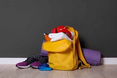 Photo of Backpack and sports equipment on floor near gray wall