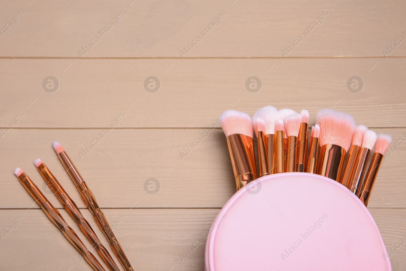 Photo of Set of professional makeup brushes with bag on wooden background, above view. Space for text