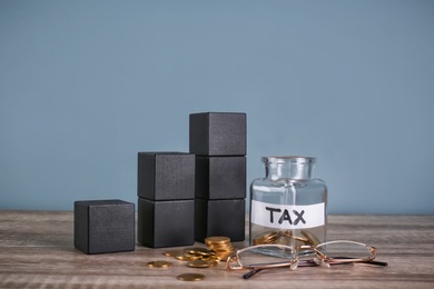 Photo of Cubes, glass jar with label "TAX" and coins on table