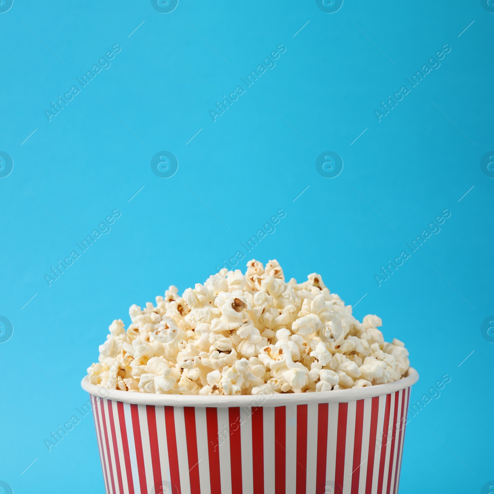 Photo of Delicious popcorn on light blue background, closeup