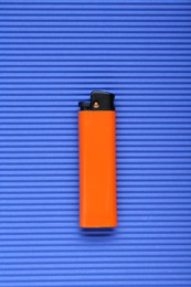 Stylish small pocket lighter on blue corrugated fiberboard, top view