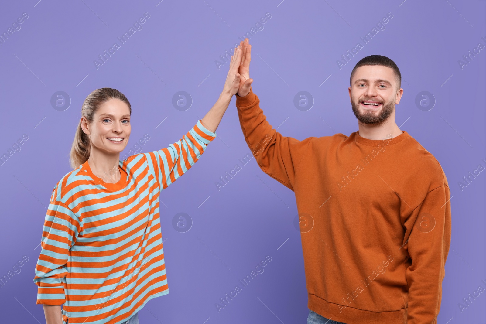 Photo of Happy couple giving high five on purple background