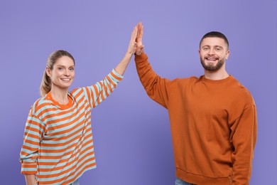 Happy couple giving high five on purple background
