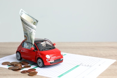 Toy car, money and insurance contract on table. Space for text