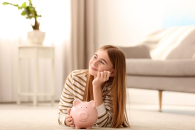 Photo of Teen girl with piggy bank at home