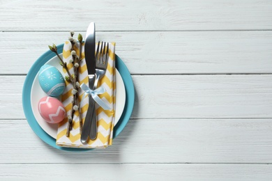 Festive Easter table setting with painted eggs on wooden background, top view. Space for text