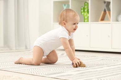 Children toys. Cute little boy playing with wooden car on rug at home