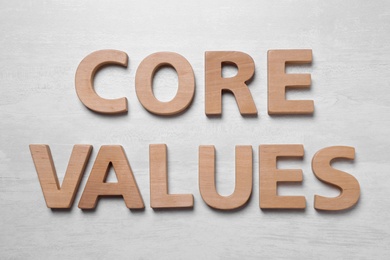 Photo of Phrase CORE VALUES made of wooden letters on white background, flat lay
