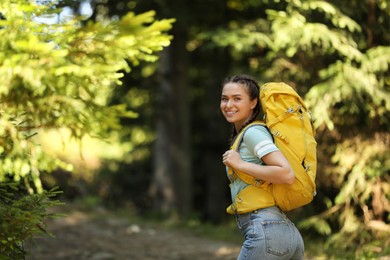 Photo of Tourist with yellow backpack going through forest