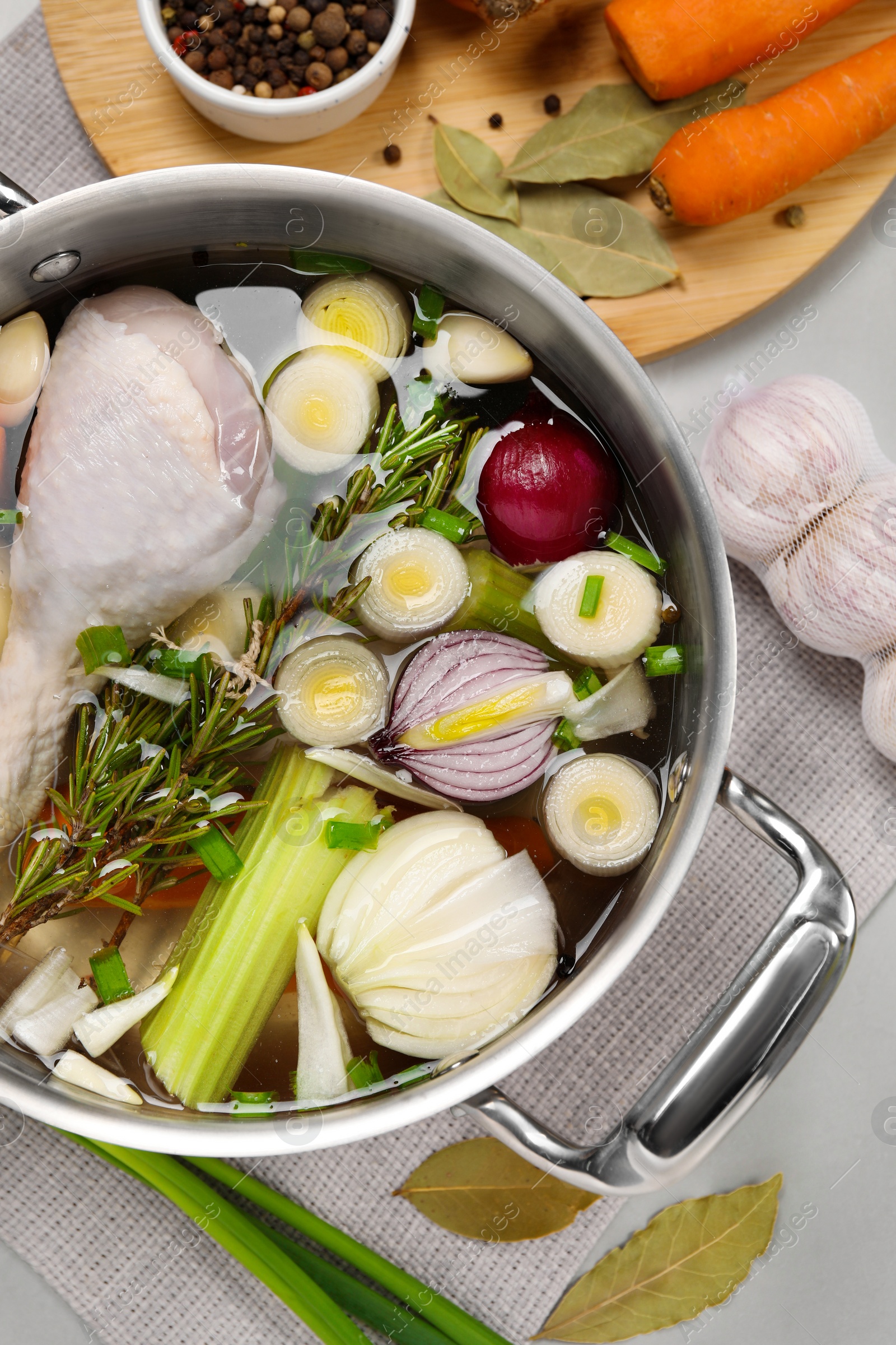 Photo of Pot and different ingredients for cooking tasty bouillon on light grey table, flat lay