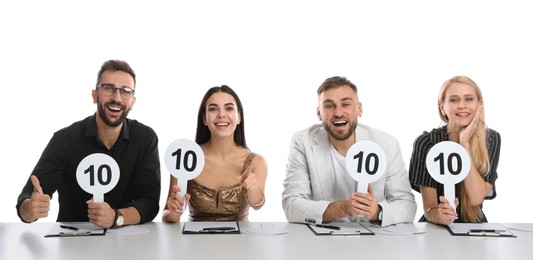 Panel of judges holding signs with highest score at table on white background