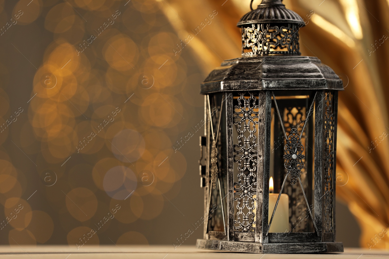 Photo of Arabic lantern on table against blurred lights, space for text