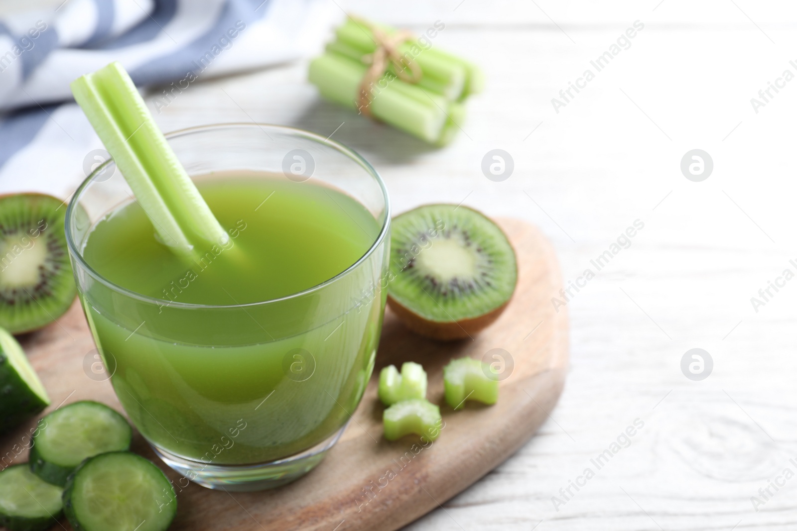 Photo of Glass of fresh celery juice on white wooden table, closeup. Space for text