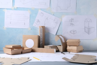 Photo of Creating packaging design. Drawings, boxes and stationery on table, closeup