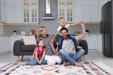 Photo of Happy family having fun together on soft rug at home