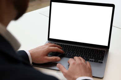 Photo of Man working on laptop at white desk in office, closeup