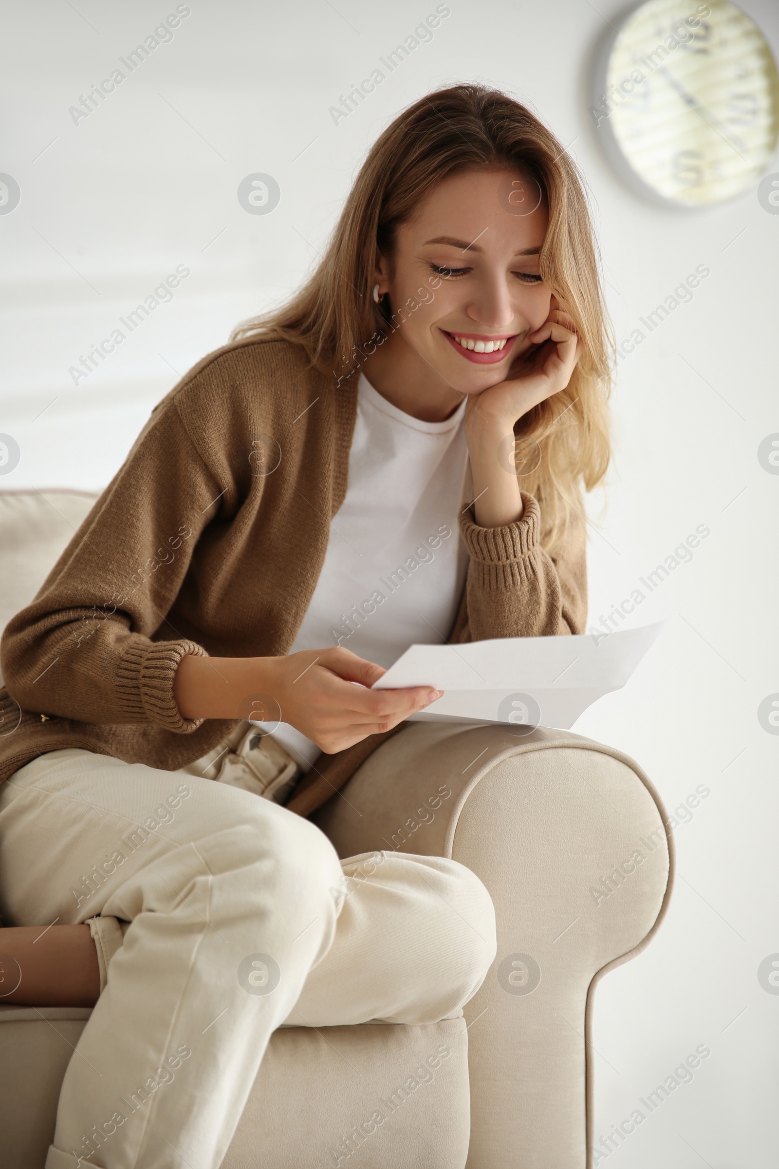 Photo of Happy woman reading letter on sofa at home