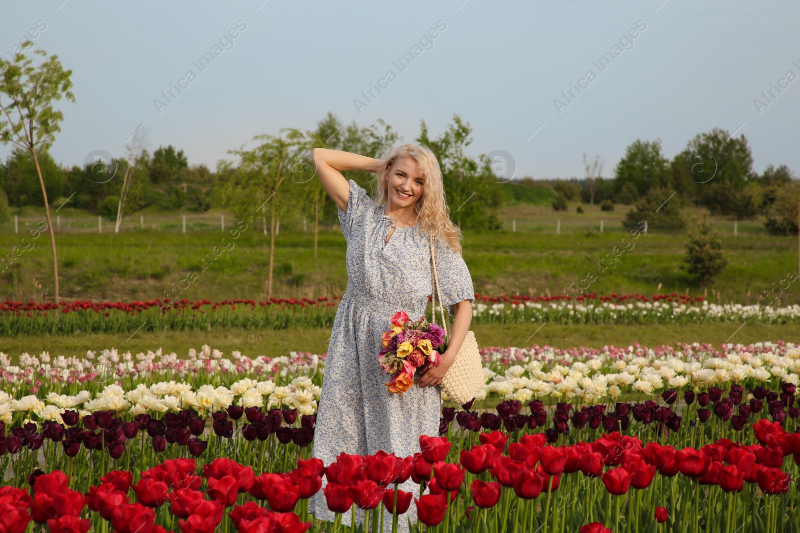 Photo of Woman with bag of spring flowers in beautiful tulip field