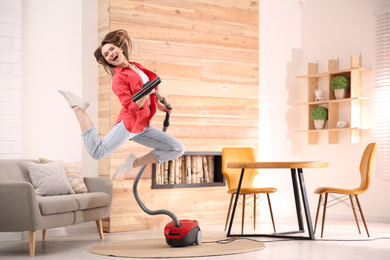 Young woman having fun while vacuuming at home