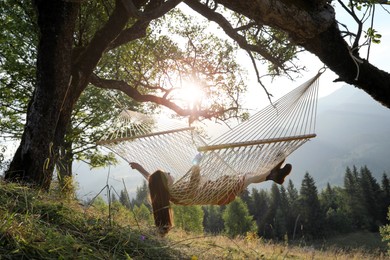Photo of Young woman resting in hammock outdoors at sunset