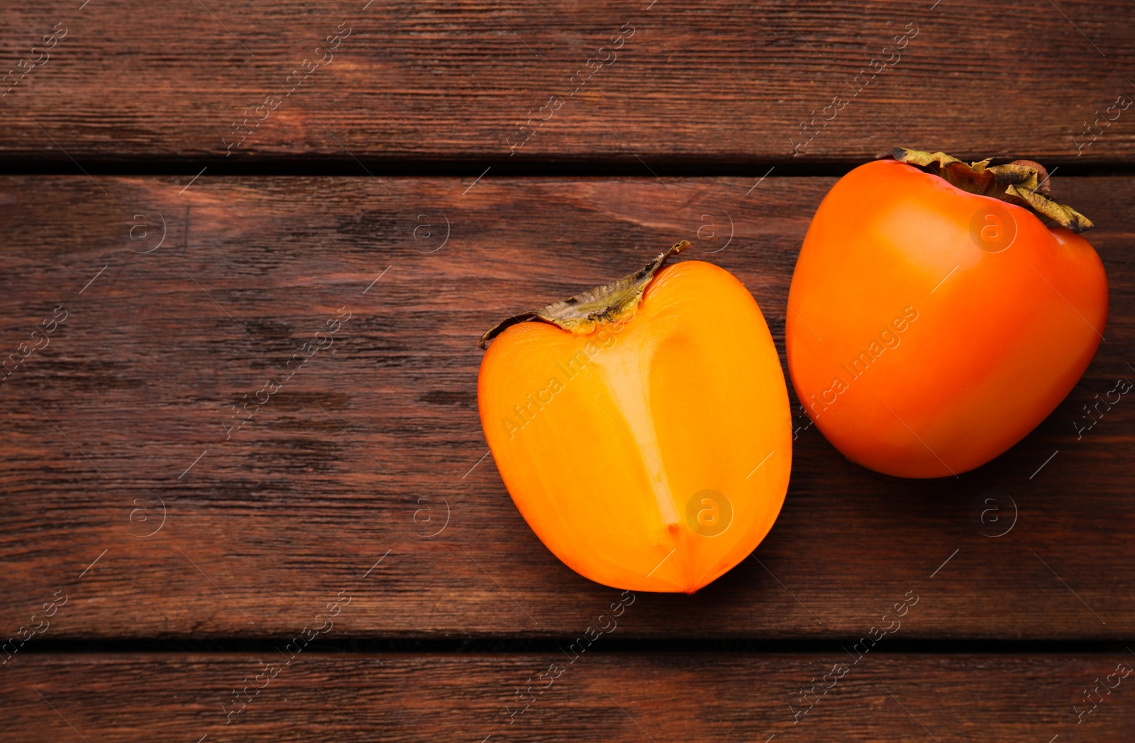 Photo of Delicious ripe persimmons on wooden table, flat lay. Space for text