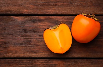 Photo of Delicious ripe persimmons on wooden table, flat lay. Space for text