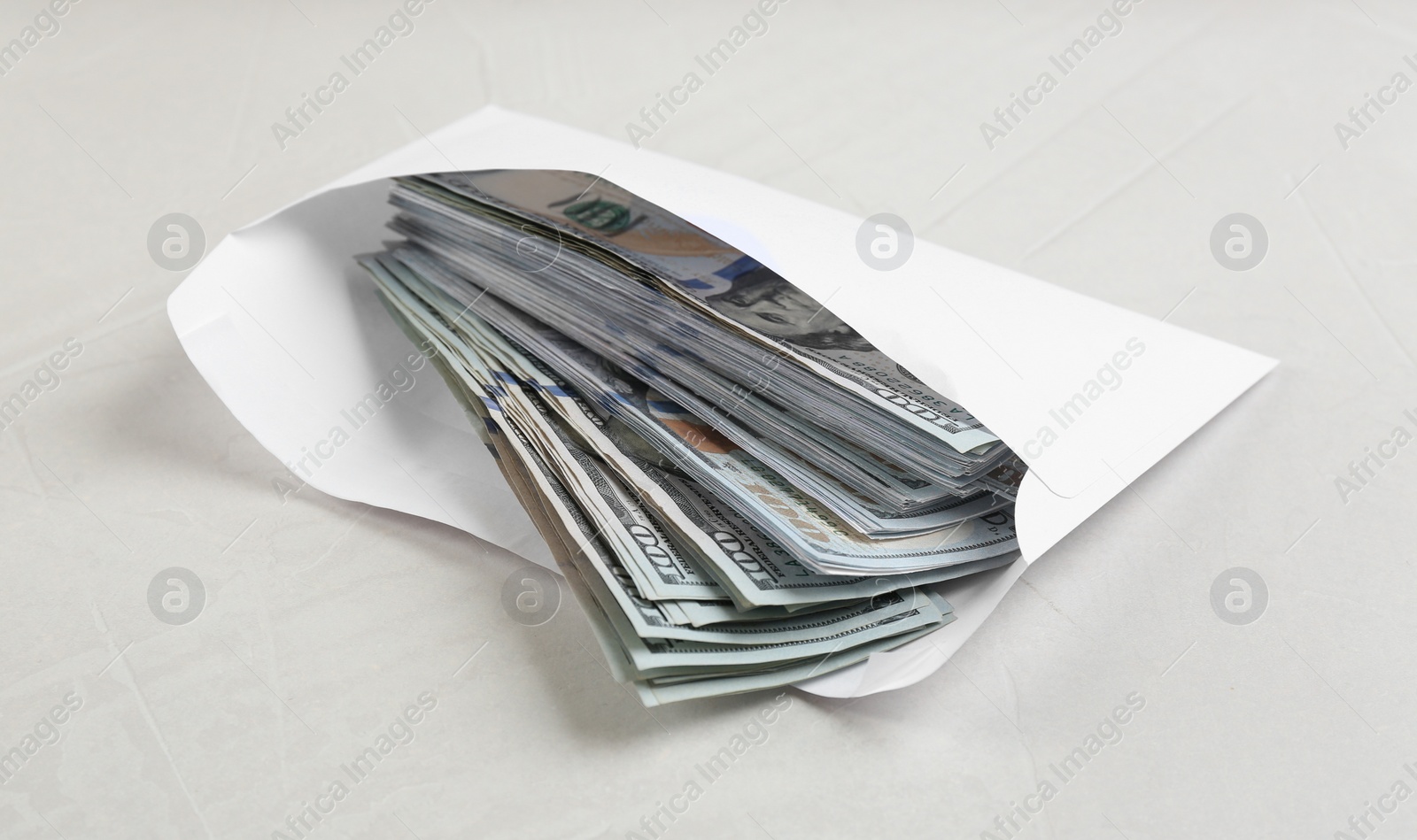 Photo of Envelope with dollar bills on light grey stone table. Bribe concept