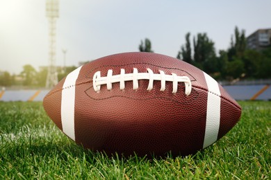 Photo of American football ball on green field grass in stadium