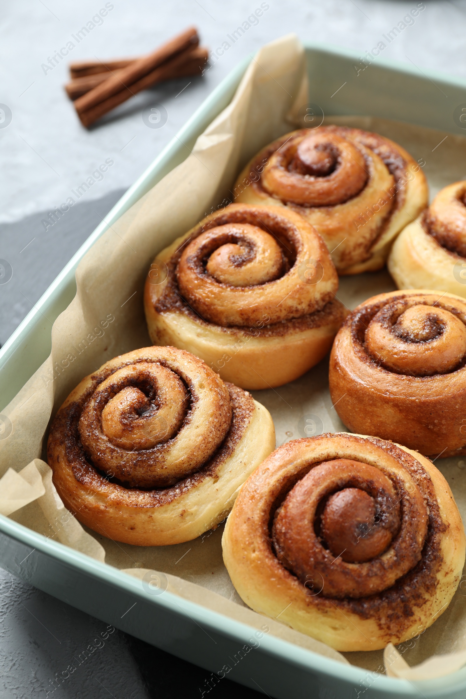 Photo of Baking dish with tasty cinnamon rolls on grey table, closeup