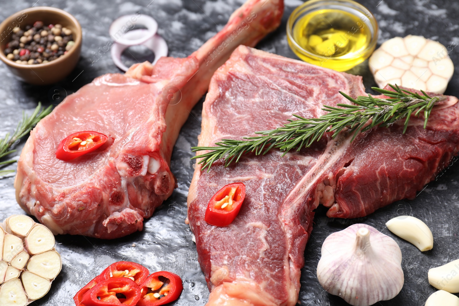 Photo of Fresh raw beef cuts and different spices on grey textured table, closeup