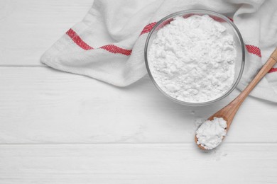 Photo of Bowl and spoon of starch on white wooden table, top view. Space for text